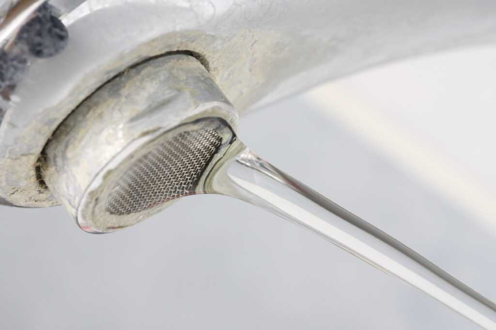 Faucet with hard water stains and water running from it